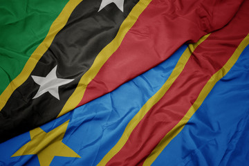 waving colorful flag of democratic republic of the congo and national flag of saint kitts and nevis.