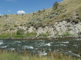Close up of part of the Yellowstone River flowing along the road and right next to a rocky mountain toward Gardiner, Montana.