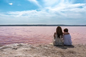 Fototapeta na wymiar cute teenager brothers sitting on a shore of amazing pink lake