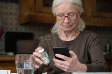 Senior woman with pill bottle using smart phone at home