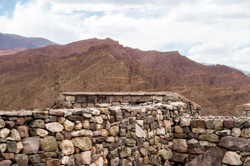 Stone wall at the archaeological site Pucara de Tilcara with mountains in the background in Jujuy, Argentina