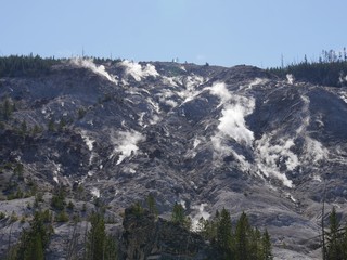 Upward view of the Roaring Mountain with steam spewing from numerous fumaroles at Yellowstone National Park, Wyoming.