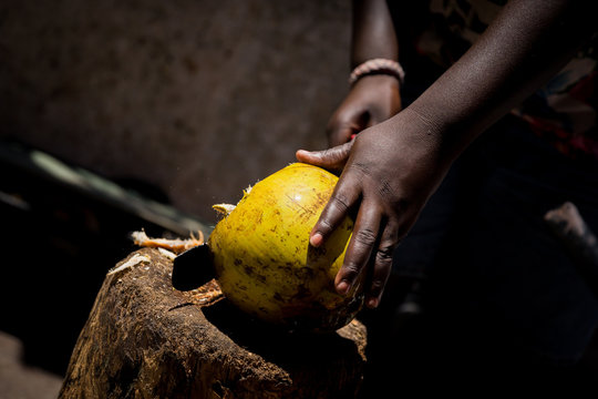 A man chops a coconut with a machete
