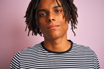 Afro american man with dreadlocks wearing navy striped t-shirt over isolated pink background with a confident expression on smart face thinking serious