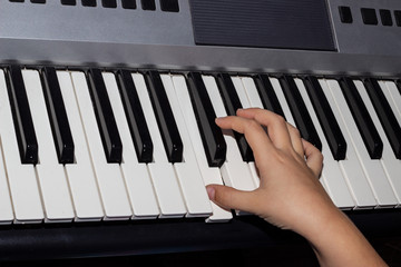 Close-up of a child's hand playing a synthesizer. Hand of a child playing the piano keyboard.