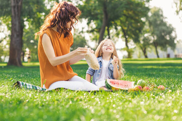 girl and woman having picnic in the park together