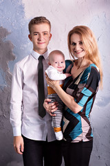 family portrait of three. mother with two sons. one adult teenager second babe. Stand in a studio