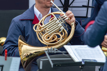 Male musician plays horn (valtorna) musical instrument. Front view.