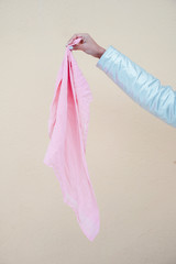 A woman hand holding the pink scarf. Concept beat cancer