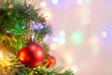 Christmas decoration. Hanging red balls on pine branches Christmas tree garland and ornaments over abstract bokeh background with copy space.