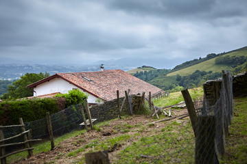 Farm buildings and fence, rural landscape at cloudy summer day, tiled roof farm building. Countryside, Atlantic Pyrenees, France. Overcast weather