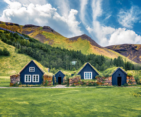 Fototapeta na wymiar Great summer view of typical Icelandic turf-top houses. Colorful summer morning in the Skogar village, south Iceland, Europe. Traveling concept background..