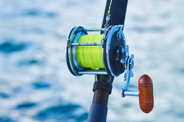 Trolling fishing boat rod and golden saltwater reel deep blue ocean sea wake. Dominican Republik...