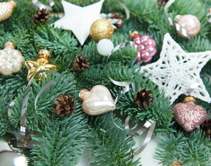 Christmas or New Year background: fir tree branches, glass balls, decoration and cones on a white plaster background