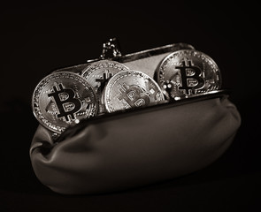 Metal Bitcoins in leather wallet on black background