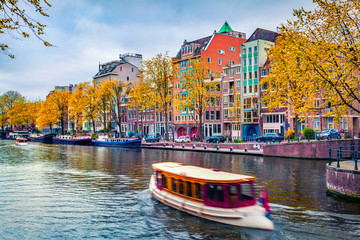 Picturesque autumn cityscape of Amsterdam. Splendid view of famous Dutch channels and excursion...