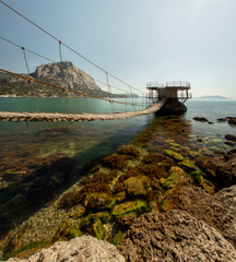 suspension bridge over water to a house on the water