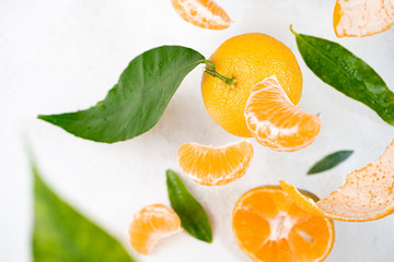 Tangerine, mandarines, clementine, citrus fruits with green leaves falling on white. Fresh tangerines citrus fruits background. Top view, copy space