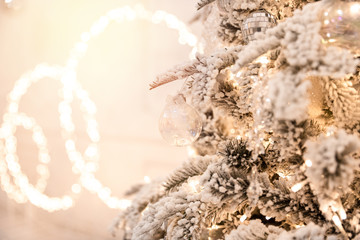 Christmas tree background with artificial snow decorated toys balls, snowflakes, branch golden illumination