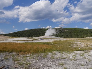 Wide scenic view of the Old Faithful geyser beginning to erupt early in the morning at Yellowstone National Park, Wyoming.