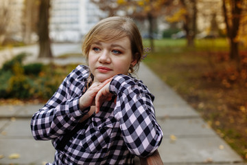 girl in a plaid shirt on a background of autumn leaves
