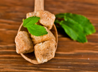 Stevia leaves with brown sugar in a wooden spoon on a wooden background
