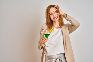 Redhead caucasian business woman drinking a summer cocktail over isolated background with happy face smiling doing ok sign with hand on eye looking through fingers