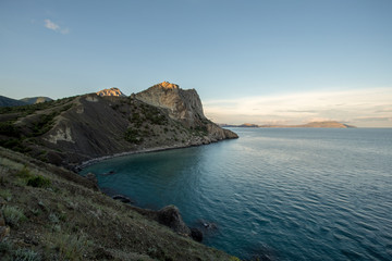 Mountains on the beach at sunset, cliffs and the sea