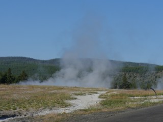 Old Faithful geyser releasing steam during an eruption at Yellowstone National Park.