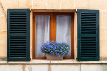 Fototapeta na wymiar House window with shutters and flowers. Beautiful Spanish architecture. Majorca island. Spain