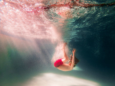 Underwater view of a boy jumping into a swimming pool