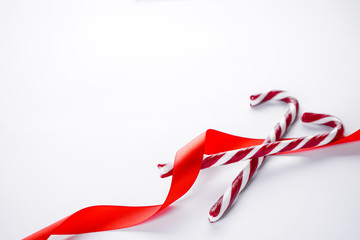 Obraz na płótnie Canvas Christmas concept Christmas candy cane with red ribbon on a white background. Copy space.