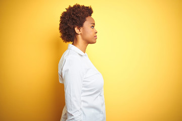 African american business woman over isolated yellow background looking to side, relax profile pose...