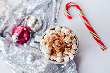 Obraz na płótnie Canvas a cup of cacao with marshmallows stands on a white table with Christmas decoration, top view flat layout style 