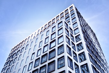 Modern European building. White building with many windows against the blue sky. Abstract architecture, fragment of modern urban geometry.