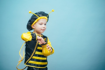 Small funny boy in a bee costume. Cute boy dressed in carnival costume. A cute little bee is eating...
