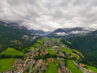Fototapeta na wymiar Beautiful aerial panoramic view of the Dolomites Alps, Italy. Mountains covered by clouds and fog. Catinaccio mountain ranges. Fassa Valley, Val di Fassa on the background