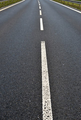 Photo of dark asphalted road and metall barrier