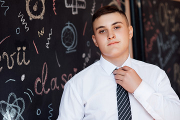 Back to school and education concept.  Portrait of handsome young male student near chalkboard