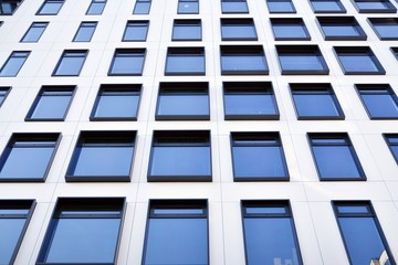 Modern European building. White building with many windows against the blue sky. Abstract architecture, fragment of modern urban geometry.