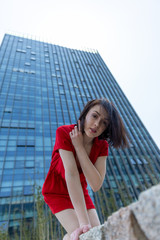 young woman in front of office building in red dres