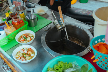 Street kitchen Pork soup with with noodles and herbs in Asia