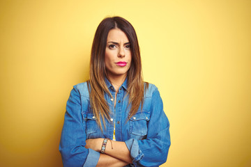 Young beautiful woman standing over yellow isolated background skeptic and nervous, disapproving expression on face with crossed arms. Negative person.