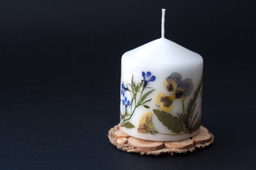 Candle with herbarium flowers. isolated on black background.