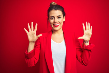 Young beautiful business woman standing over red isolated background showing and pointing up with fingers number ten while smiling confident and happy.