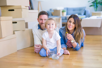 Beautiful famiily with kid lying down at new home around cardboard boxes