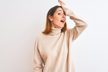 Beautiful redhead woman wearing winter turtleneck sweater over isolated background surprised with hand on head for mistake, remember error. Forgot, bad memory concept.