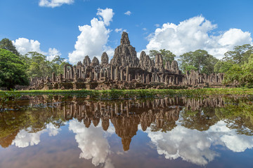 Fototapeta na wymiar Bayon temple and its perfect clear reflection in the water. Impressive clouds and a blue sky compliment the scene. Bayon g
