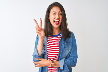 Young chinese woman wearing striped t-shirt and denim shirt over isolated white background smiling with happy face winking at the camera doing victory sign with fingers. Number two.