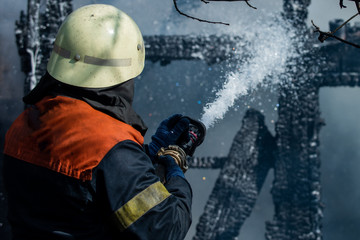 Brave firefighter saving burning building. Firefighter work concept. Firefighter are using water in fire fighting operation. Real brave hero combat the fire with foam extinguisher.